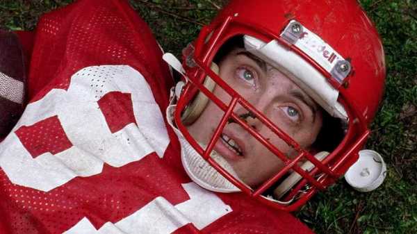 A football player with an injured face lying on the grass in The Blob 1988