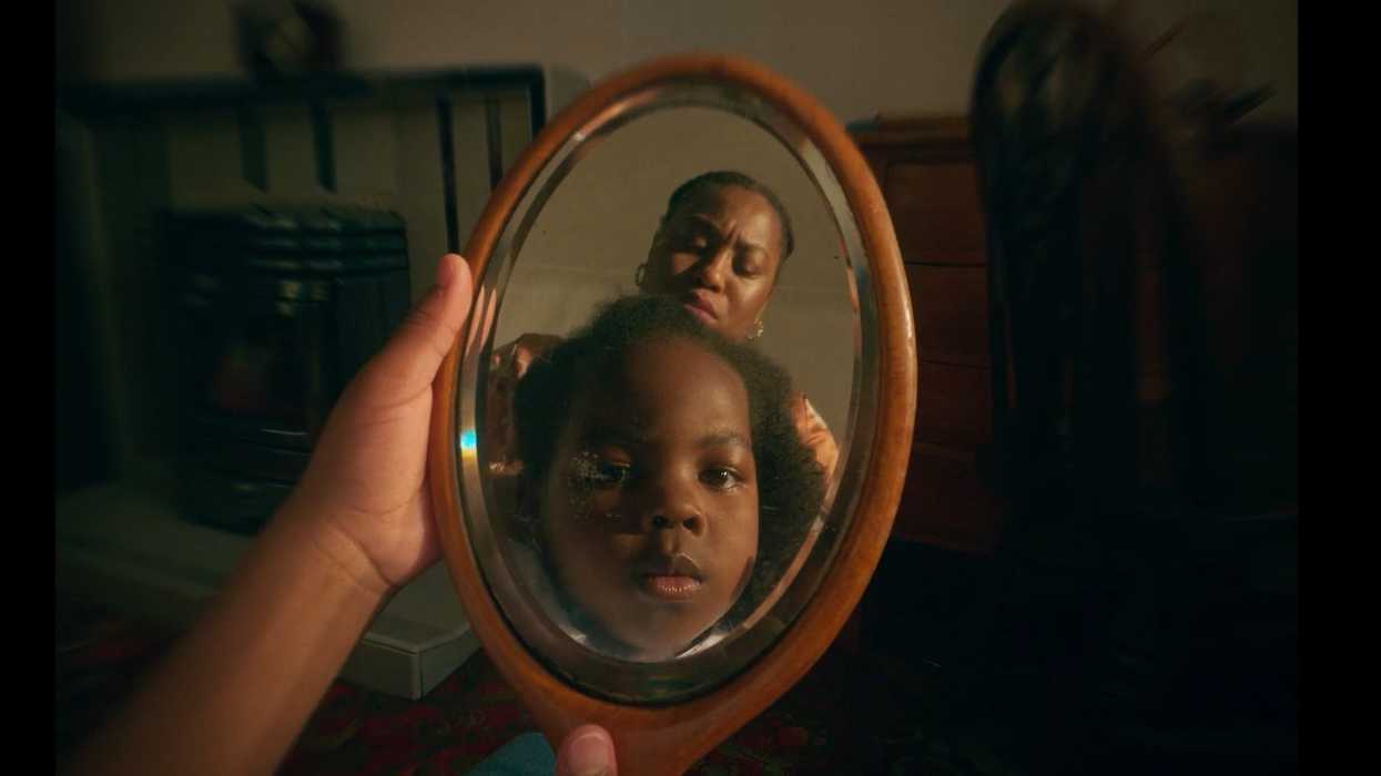 A little girl looking into a mirror while an older woman does her hair, 'Monochromatic'
