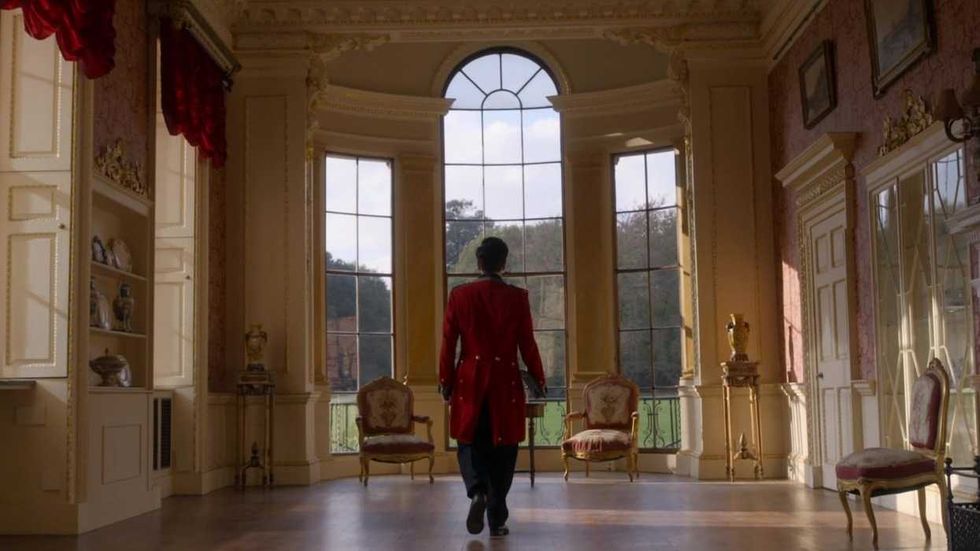 A liveried man walks toward a window in Downton Abbey 2019