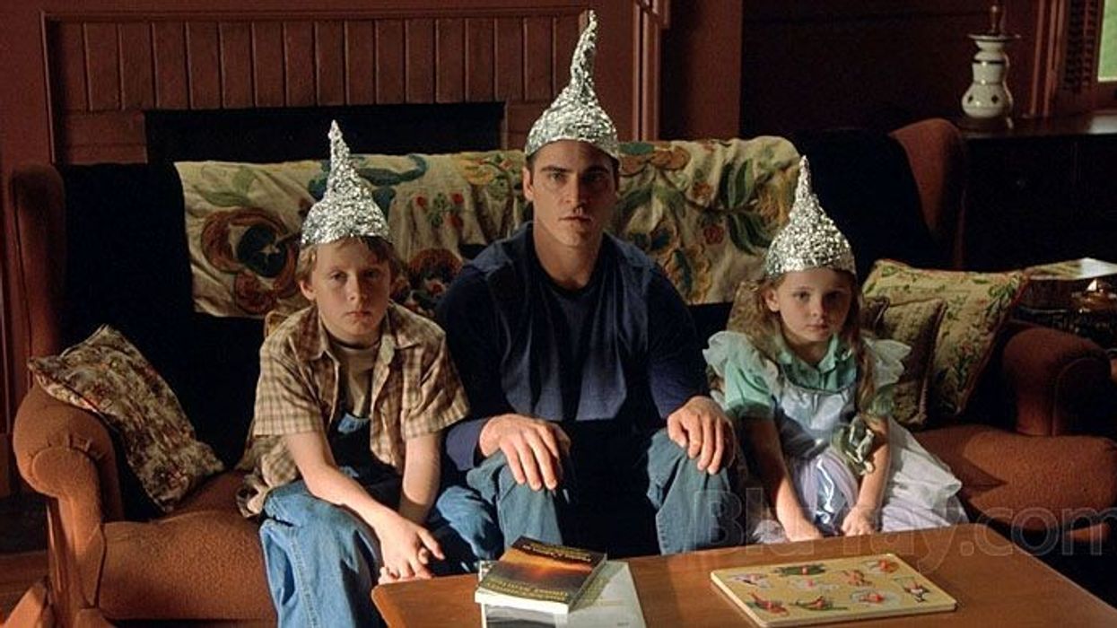 A man and two children sitting on a couch with tin foil hats in 'Signs'