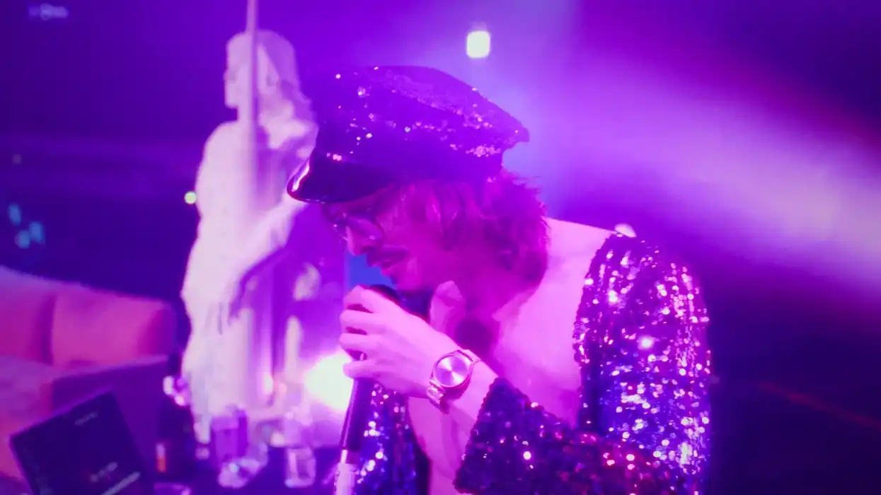 A man in sequence singing on a stage.
