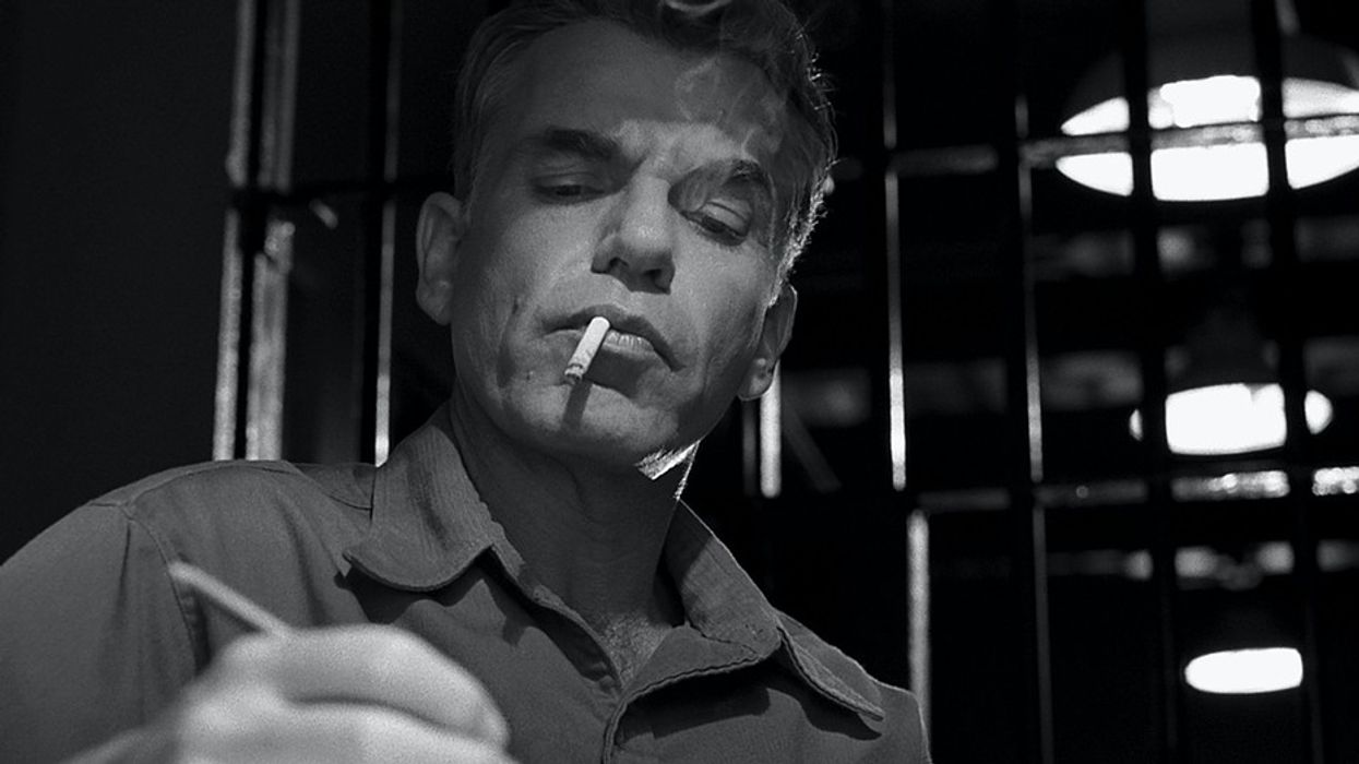 A man smoke while writing a letter in prision in 'The Man Who Wasn't There'