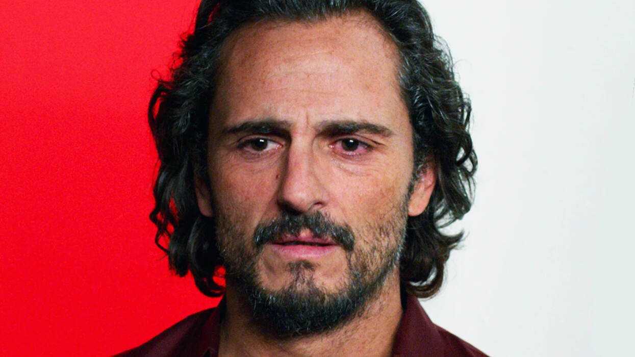 A man standing in front of a red and white background in Pain and Glory