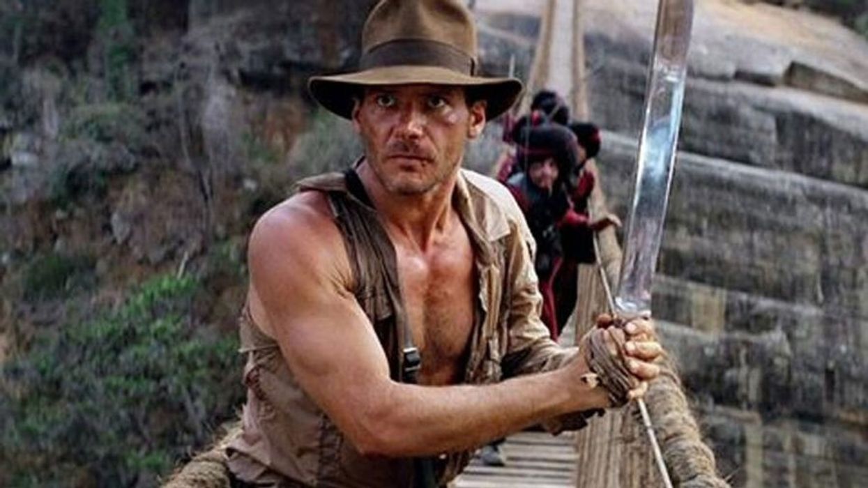 A man with a sword on a bridge in the jungle