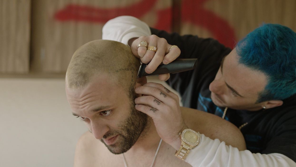 A man with blue hair shaving someone's head in 'Anchorage'