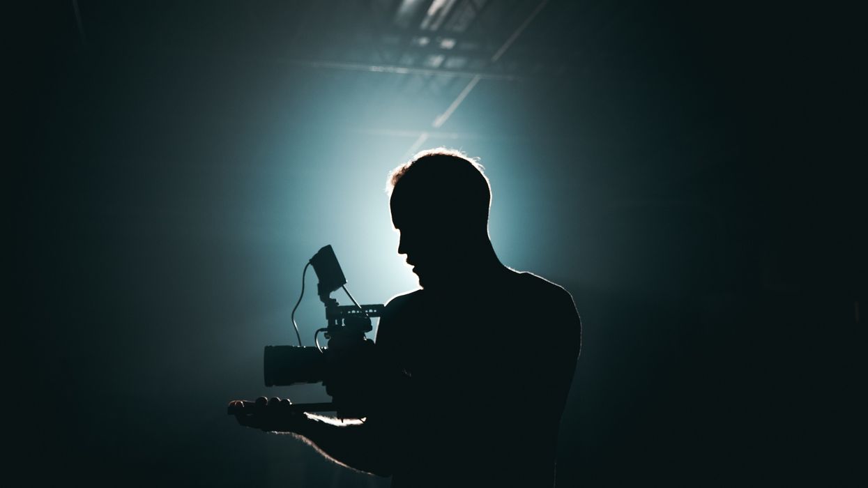 A silhouette photography of man holding camera