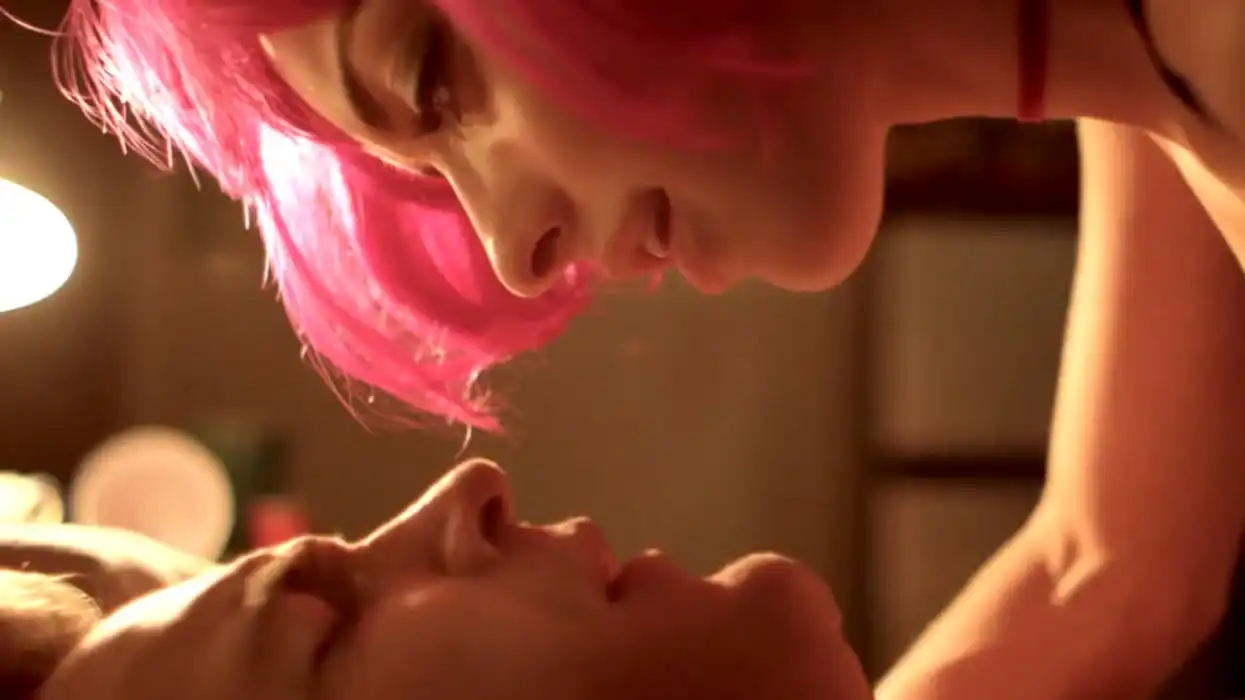 A woman in a pink wig ontop of a man, 'M.F.A.'