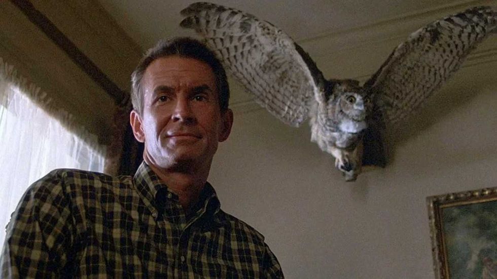 Anthony Perkins as Norman Bates standing in front of a stuffed owl in Psycho III