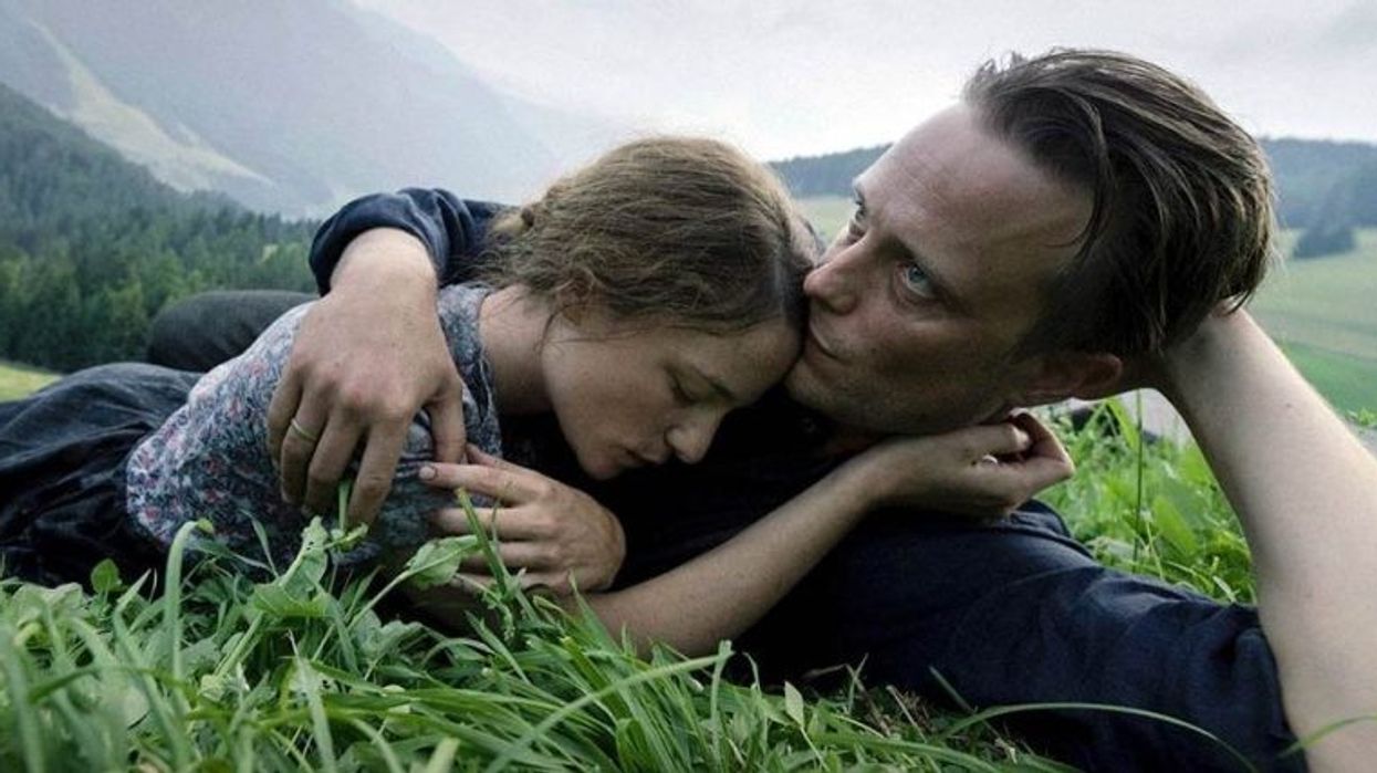 August Diehl as Franz Jägerstätter and Valerie Pachner as Franziska Jägerstätte laying in the grass in 'A Hidden Life'