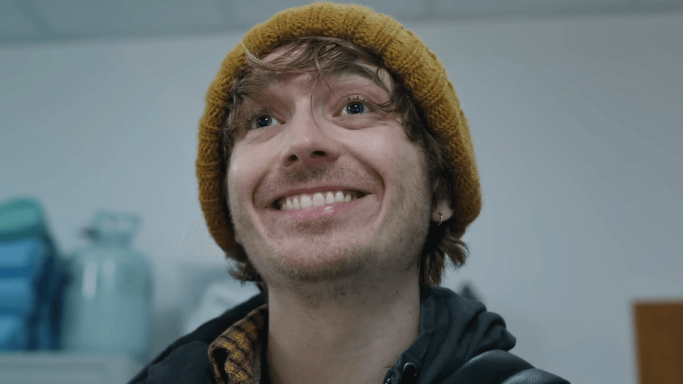 Austin Abrams wearing a mustard-yellow knit beanie in Zach Cregger's Resident Evil