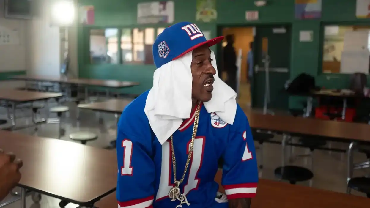 Biz Markie sitting in a school cafeteria.
