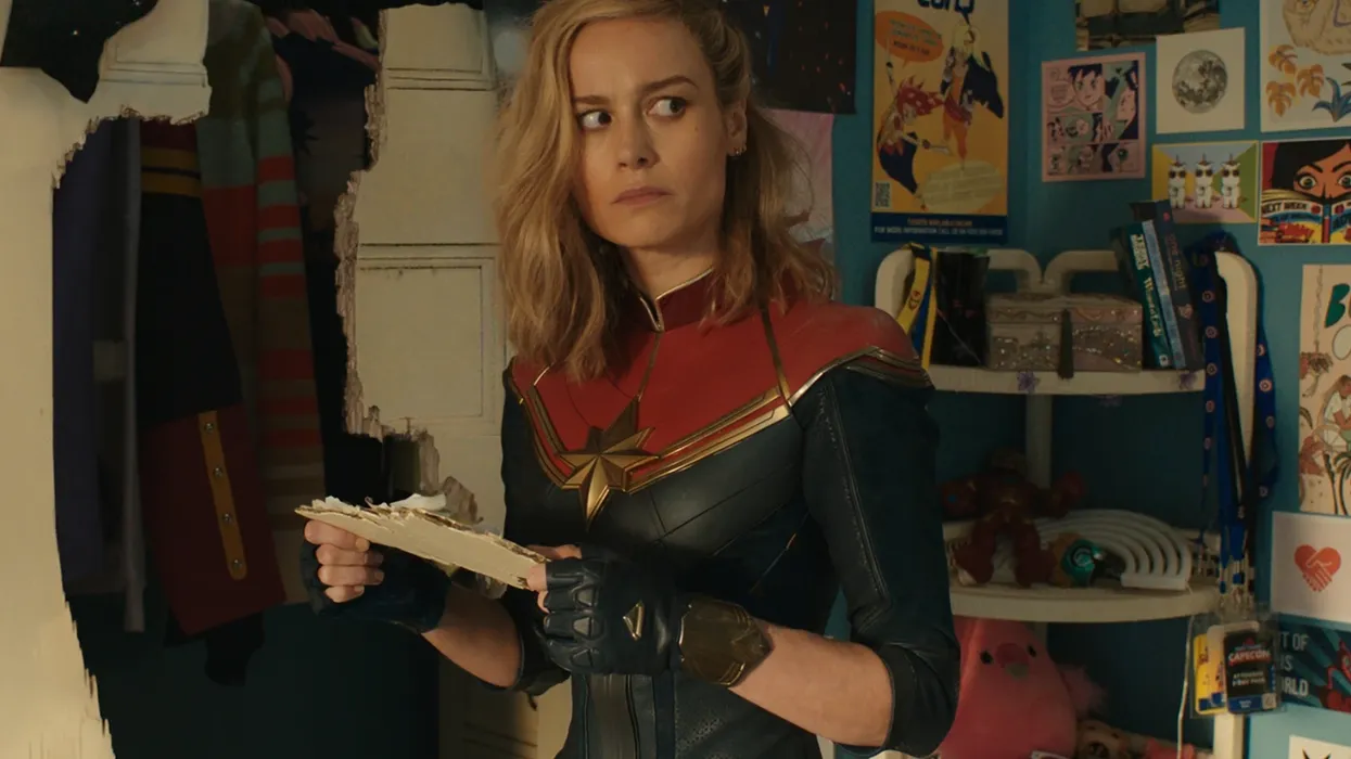 Brie Larson as Captain Marvel holding a piece of broken door in 'The Marvels'