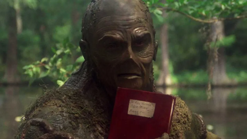 Dick Durock as Swamp Thing holding a book in Swamp Thing 1982