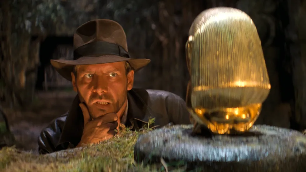 Harrison Ford as Indiana Jones examining the golden fertility idol in the 1981 film Raiders of the Lost Ark