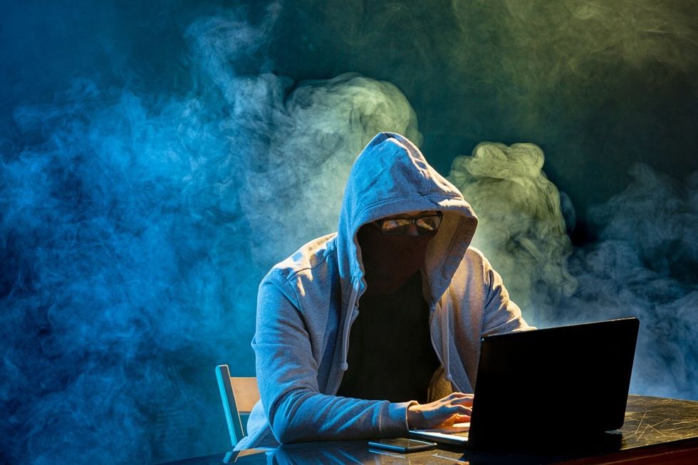 Hooded-computer-hacker-stealing-information-with-pzxtq33