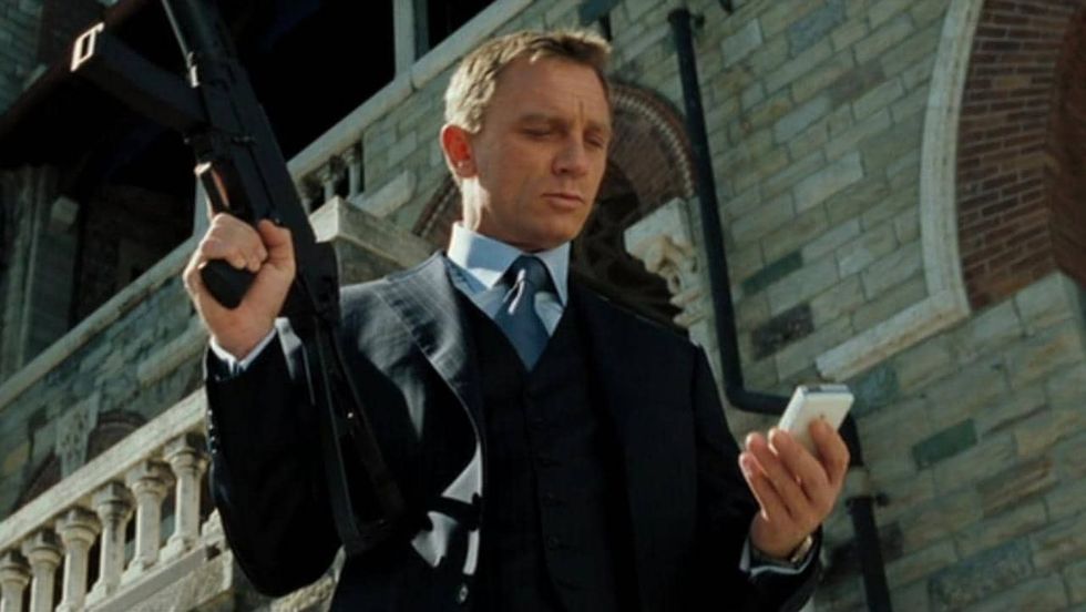 James Bond, played by Daniel Craig, looking at a phone in 'No Time to Die'