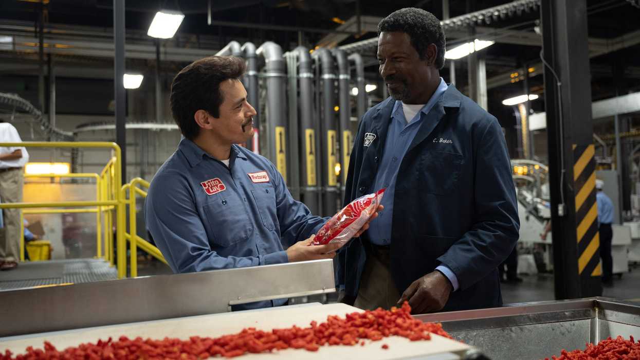 Jesse Garcia as Richard Montañez and Dennis Haysbert as Clarence C. Baker standing in front of flmain' hot chettos in 'Flamin' Hot'