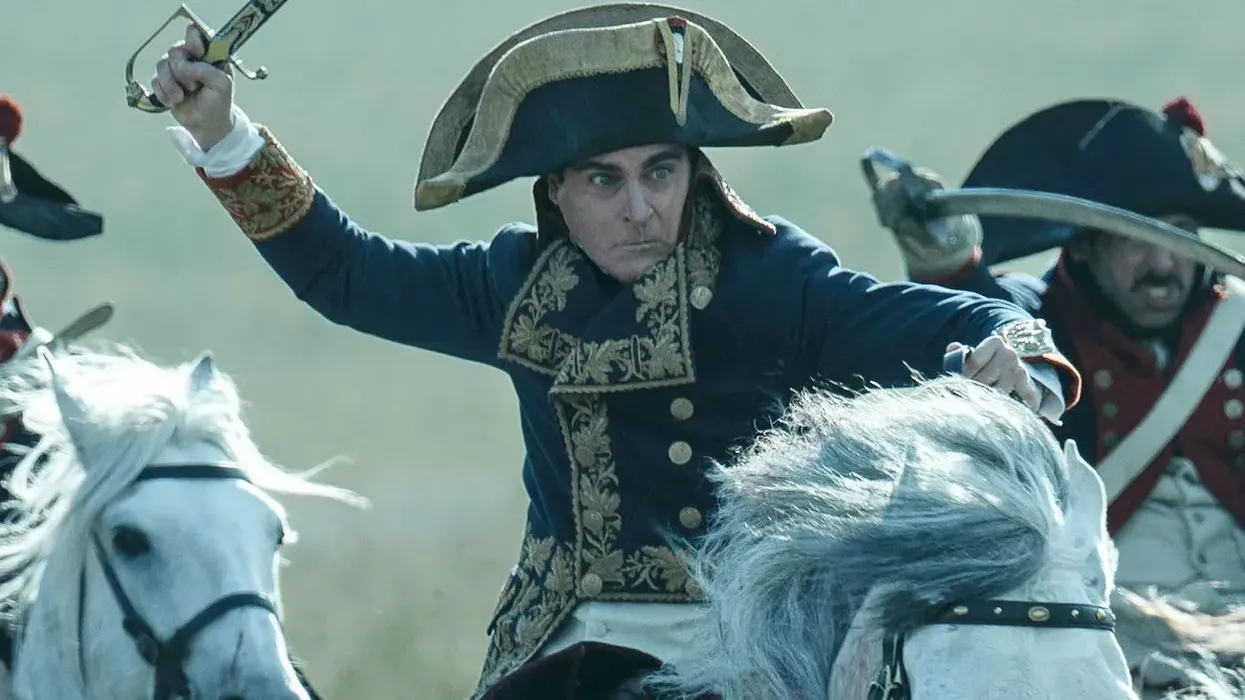 Joaquin Phoenix as Napoleon Bonaparte riding a horse into battle in 'Napoleon'
