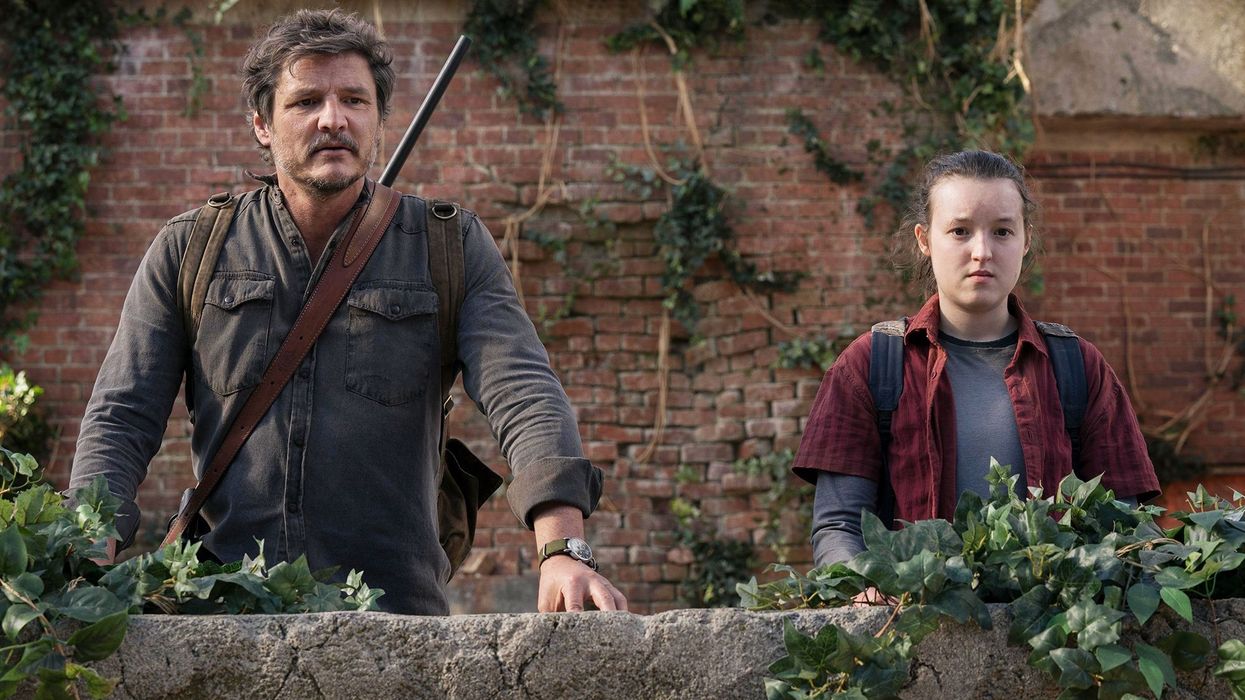 Joel, played by Pedro Pascal, and Ellie, played by Bella Ramsey, looking over an overgrown ledge in 'The Last of Us'