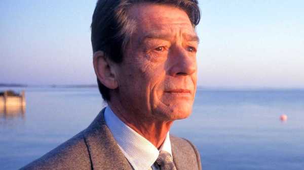 John Hurt looking pensive on a beach in Love and Death on Long Island
