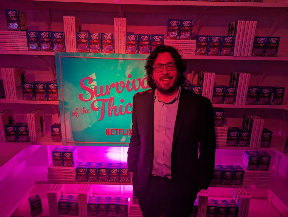 John Rafanelli standing infront of a 'Survival of the Thickest' sign