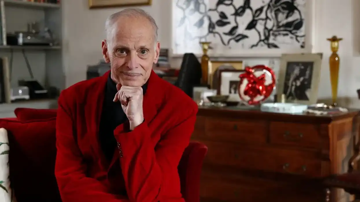 John Waters in a red jackets in his home