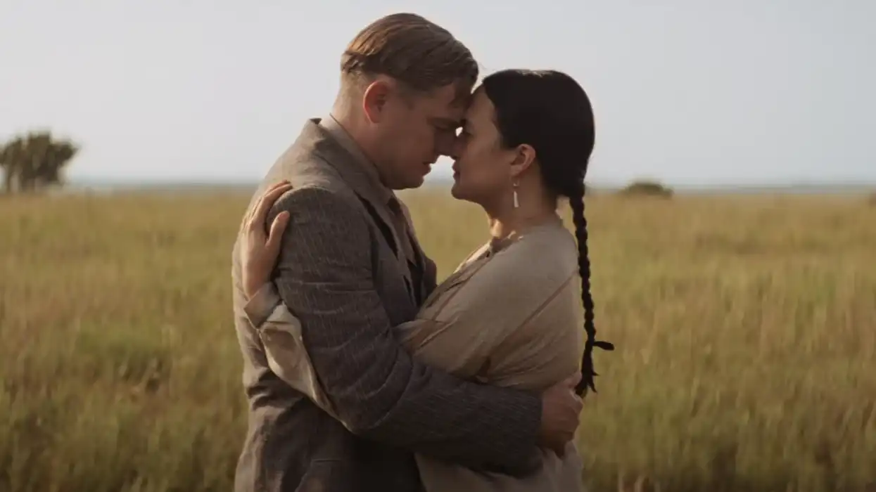 Leonardo DiCaprio as Ernest Burkhart and Lily Gladstone as Mollie Burkhart embracign in a field in 'Killers of the Flower Moon'