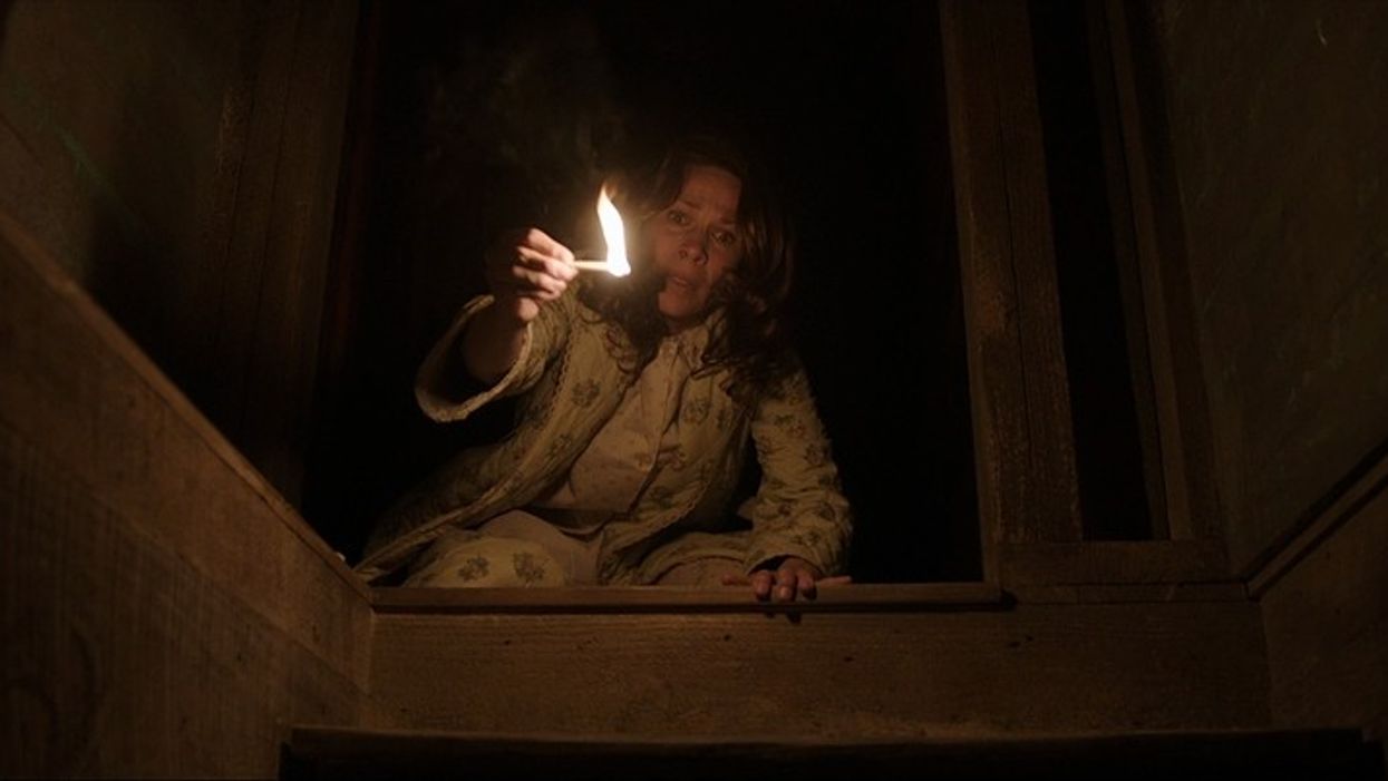 Lili Taylor as Carolyn Perron looking down the stairs with a match in 'The Conjuring'