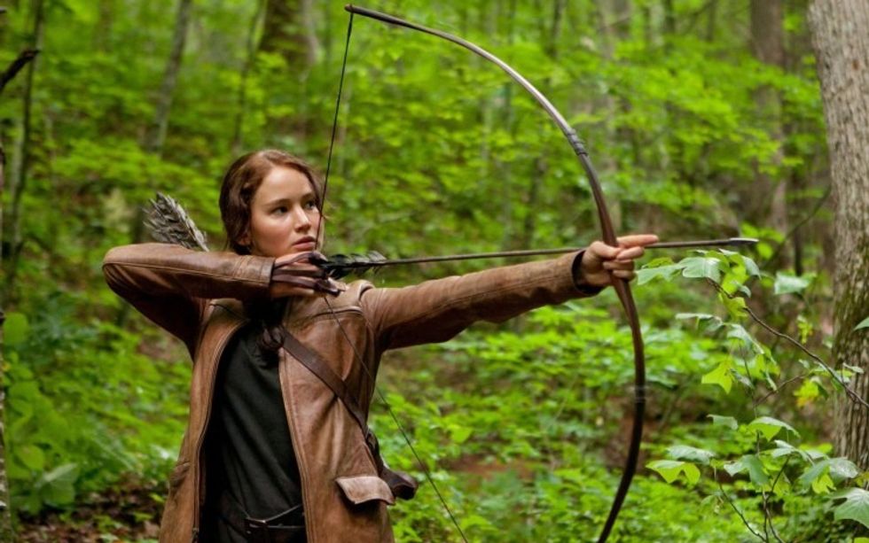Medium shot of Katniss Everdeen, played by Jennifer Lawrence, shooting an arrow in 'The Hunger Games'