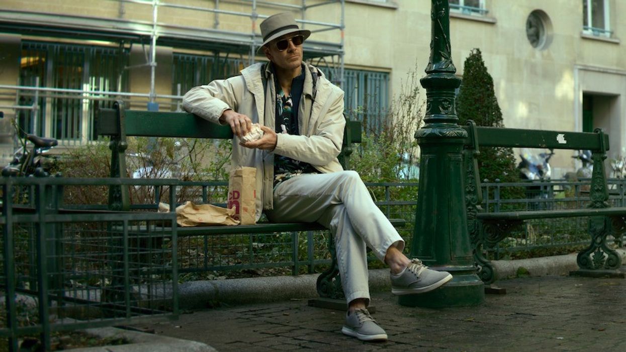 Michael Fassbender as The Killer eating in the park in 'The Killer'