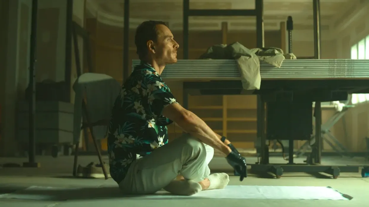 Michael Fassbender as The Killer sitting on the floor in 'The Killer'