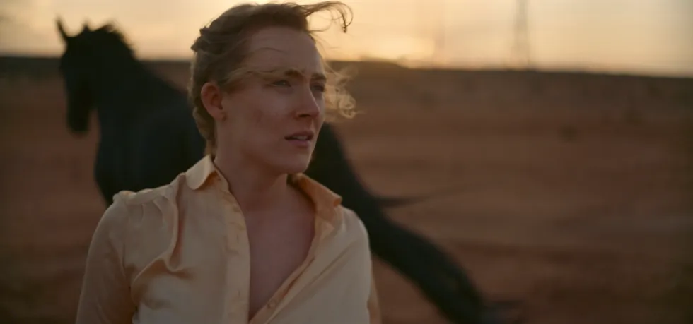 Saoirse Ronan as Henrietta staring at a horse in 'Foe'