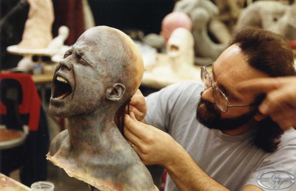 Special effects artist working on a screaming puppet head being detailed or fitted with hair in Terminator 2