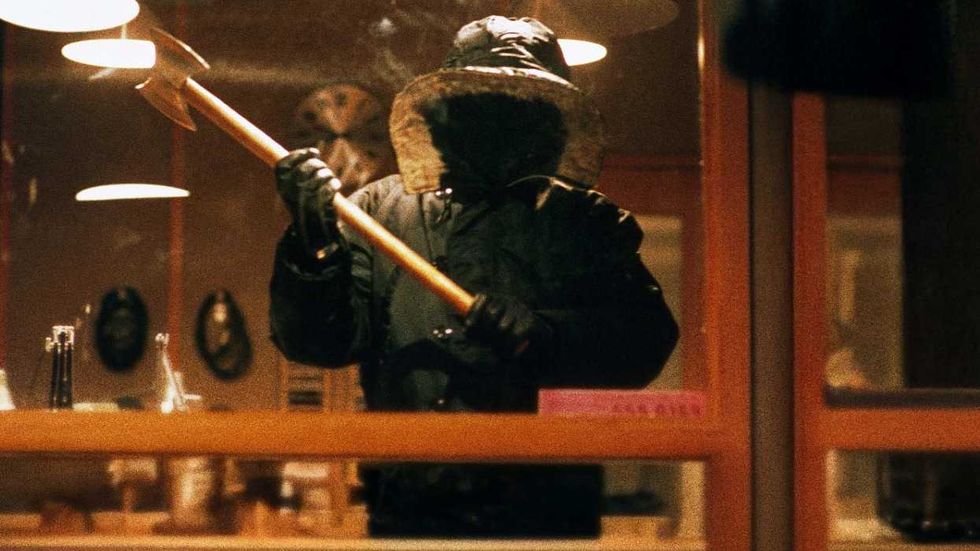 The killer from Urban Legend viewed through a window holding an axe