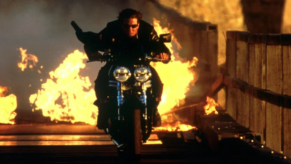 Tom Cruise as Ethan Hunt on a motorcycle driving away from an explosion, 'Mission: Impossible II'