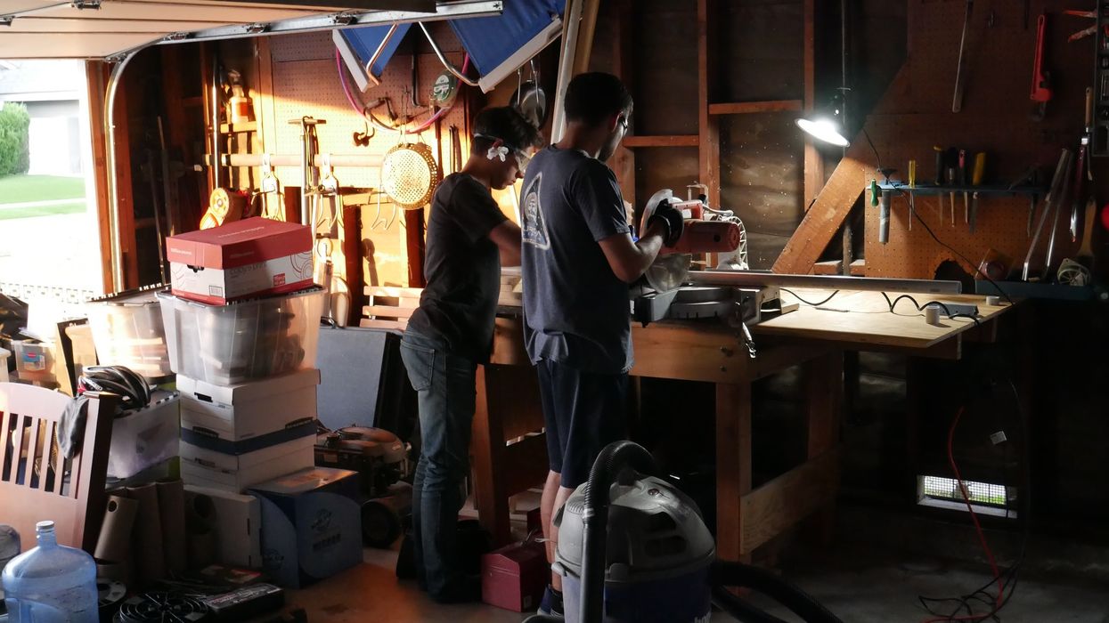 Two men building a camera rig in a garage