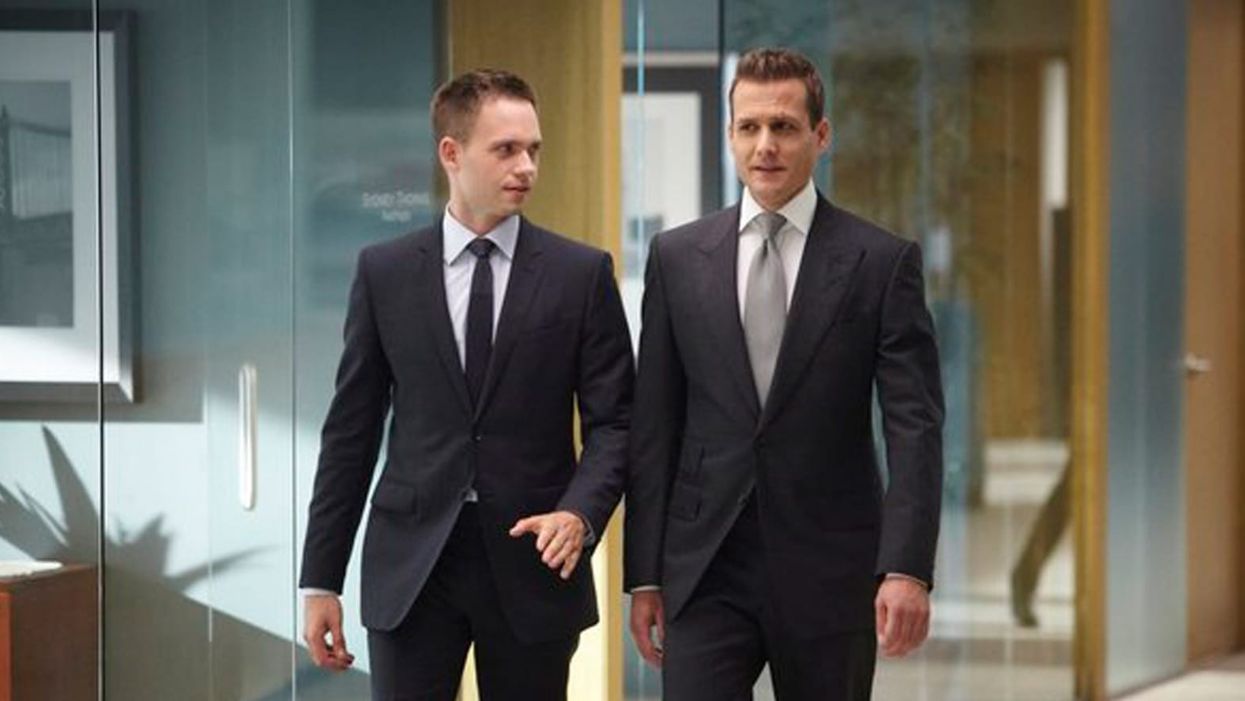 Two men in suits walking down a law office hallway.