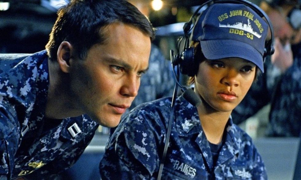 Two navy personal in uniform looking at a monitor, 'Battleship'