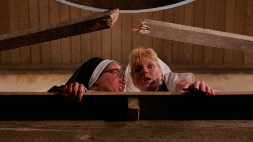 Two nuns looking fearfully over a broken railing in Psycho III