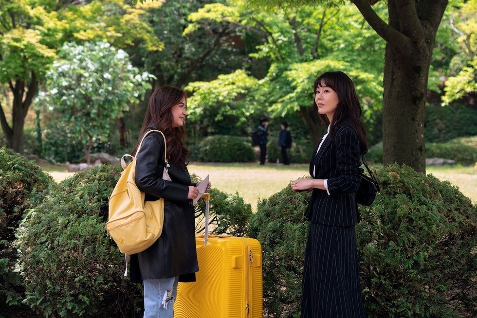 Two women standing outside with a yellow suitcase, 'Xo, Kitty'