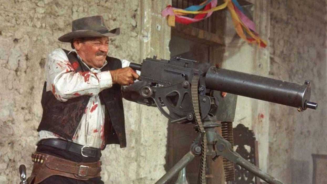 William Holden as Pike Bishop firing a mounted machine gun