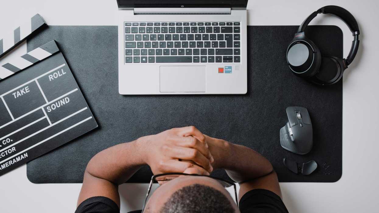 Writer at a laptop with headphones and slate nearby